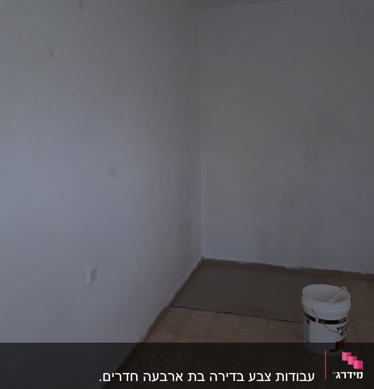 קיר לבן עם דלי צבע על הרצפה